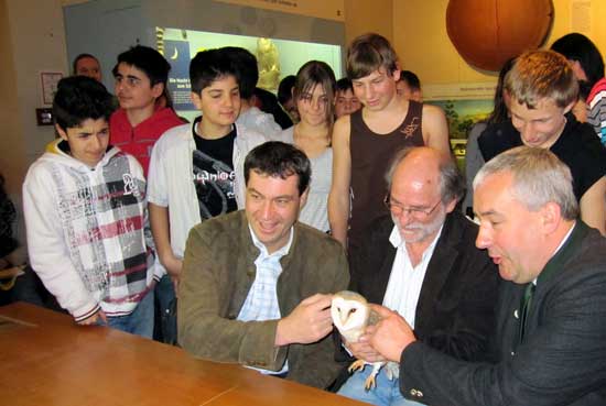 Minister of State, Dr. Markus Söder, Dr. Ludwig Spänle and the teacher Wilhelm Holzer show an owl to the students standing behind them.