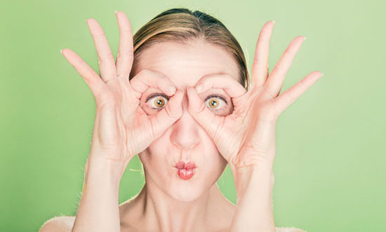 Das Gesicht einer Frau, die mit den Daumen und Zeigefingern eine Brille formt, macht große Augen und einen gekräuselten Mund (Foto: Ryan Mcguire/gratisography.com/).