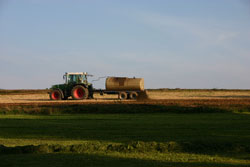 Traktor mit Gülletank auf einer Ackerfläche während der Ausbringung.