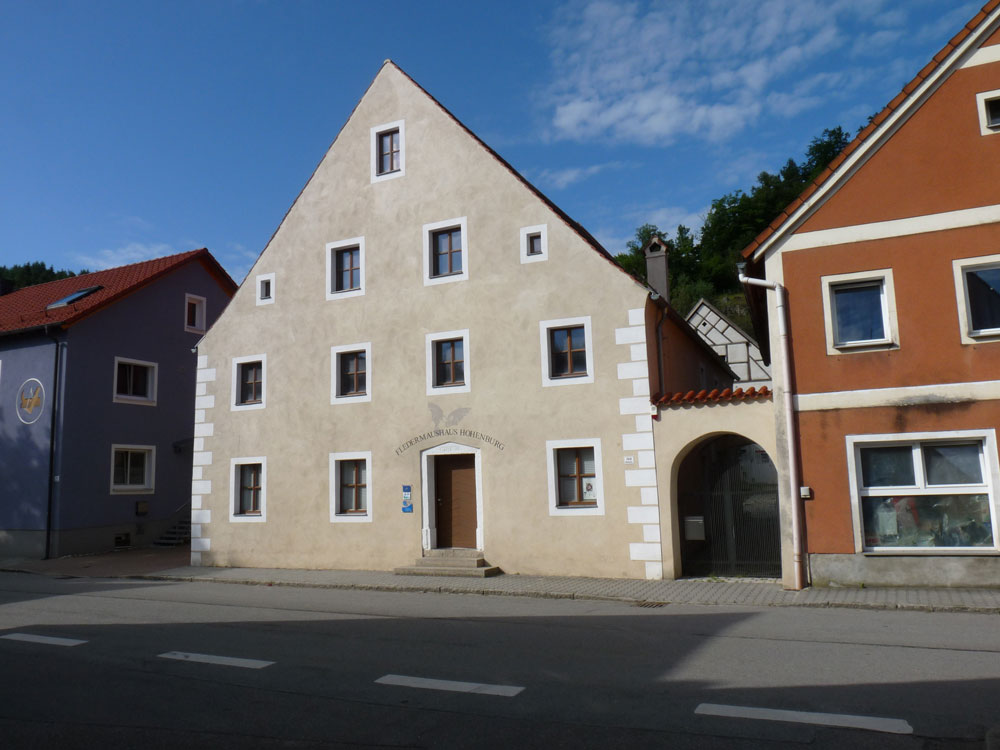 Ein vierstöckiges altes Gebäude mit heller Fassade und Spitzgiebel.