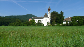 Klosteranlage mit Kirche am Rande einer artenreichen Streuwiese.