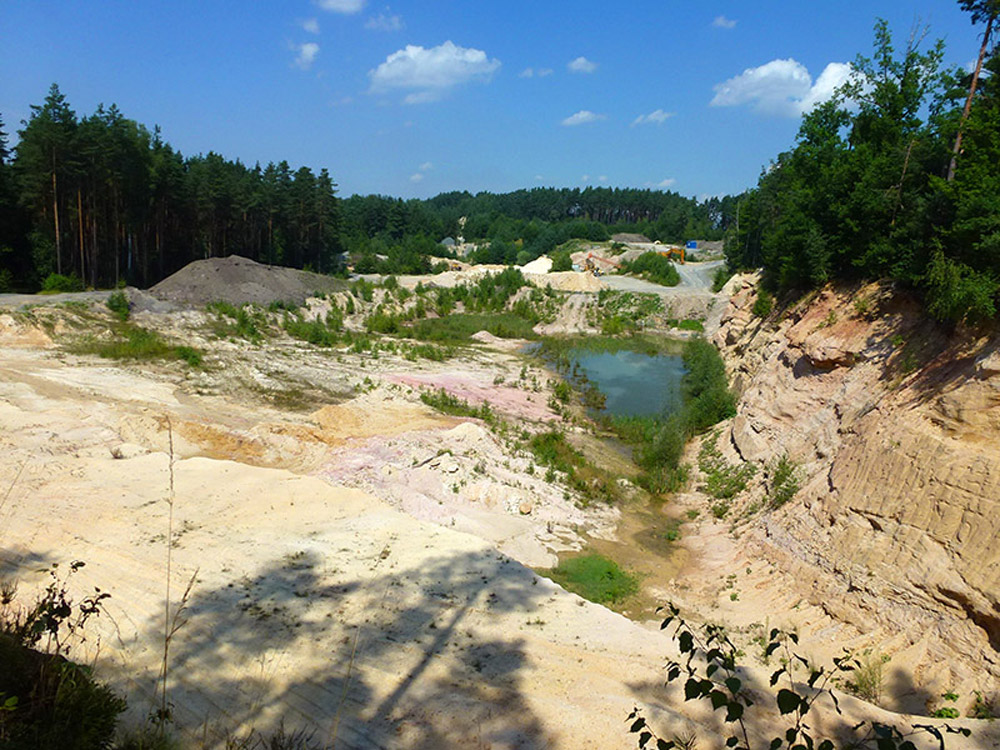 Eine offene Sandgrube mit Sand- und Wasserflächen.