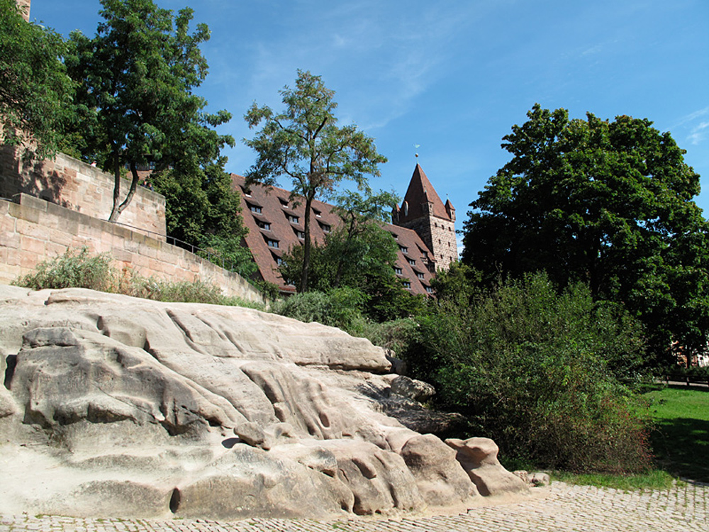 Eine steile Sandsteinmauer dominiert den Blick auf die Kaiserburg in Nürnberg.