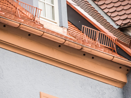 Detailansicht einer frisch renovierten Hausfassade mit Ziegeldach, Schneefang und Dachgauben.