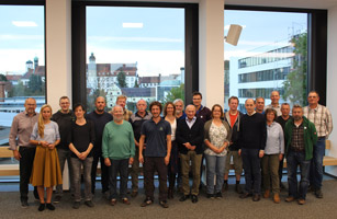 Auf dem Foto ist eine Menschengruppe mit 22 Personen abgebildet. Sie richten ihren Blick auf den Betrachter. Das Geschlechter- und Altersverhältnis ist ausgewogen. Die Personen bilden das Team der Akteure im Wiesenbrüterschutz in Schwaben.