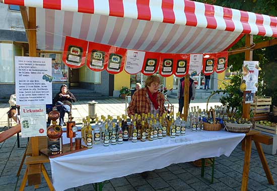 Eine ältere Frau verkauft Obstbrände am Marktstand