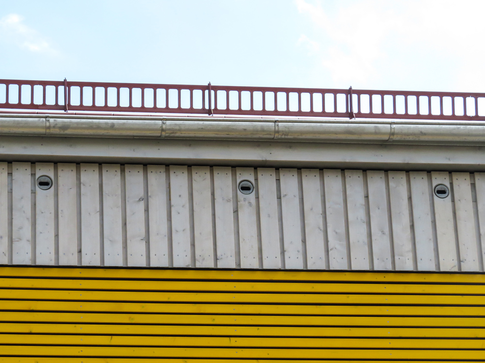 Detailansicht einer modernen Hausfassade mit drei künstlichen Einflugslöchern für Vögel.