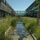 Zwei Bürogebäude, die durch eine Brücke verbundene sind. Unter dieser Brücke und zwischen den Bürogebäuden ein zentraler Wassergraben (Foto: Andreas Zehm).