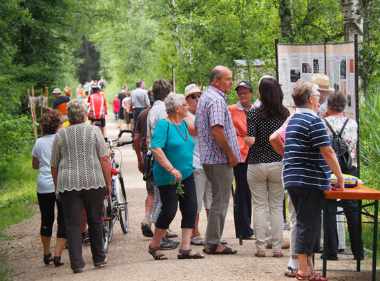 Besucher informieren sich an Schautafeln und historischen Fotos, die entlang des Weges aufgestellt sind.