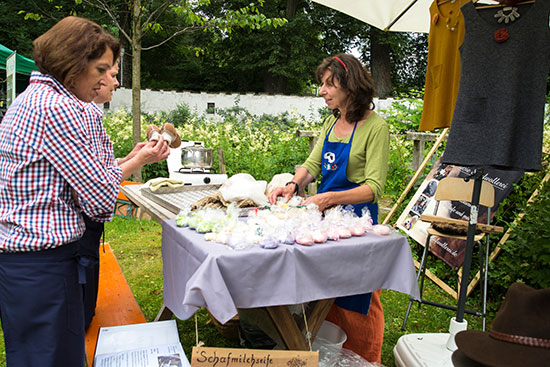 Zwei Frauen bewundern am Stand die Herstellung von Schafmilchseife.