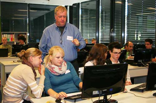 Zwei Schülerinnen und ein Lehrer arbeiten am Computer.