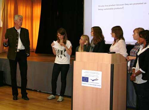 Dr. Witzmann und sechs Schülerinnen und Schüler stehen auf dem Podium neben dem Rednerpult.