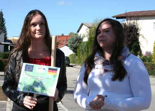 Zwei Schülerinnen zeigen ein Baumschild.