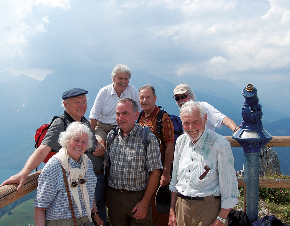 Gruppe von gutgelaunten Menschen auf einem Aussichtspunkt auf dem Berg Jenner in den Berchtesgadener Alpen bei sommerlichem Wetter.