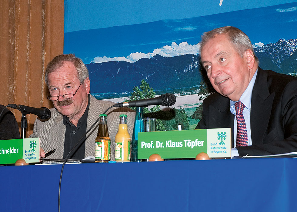 Zwei Männer auf einem Podiumstisch mit Mikrofonen.