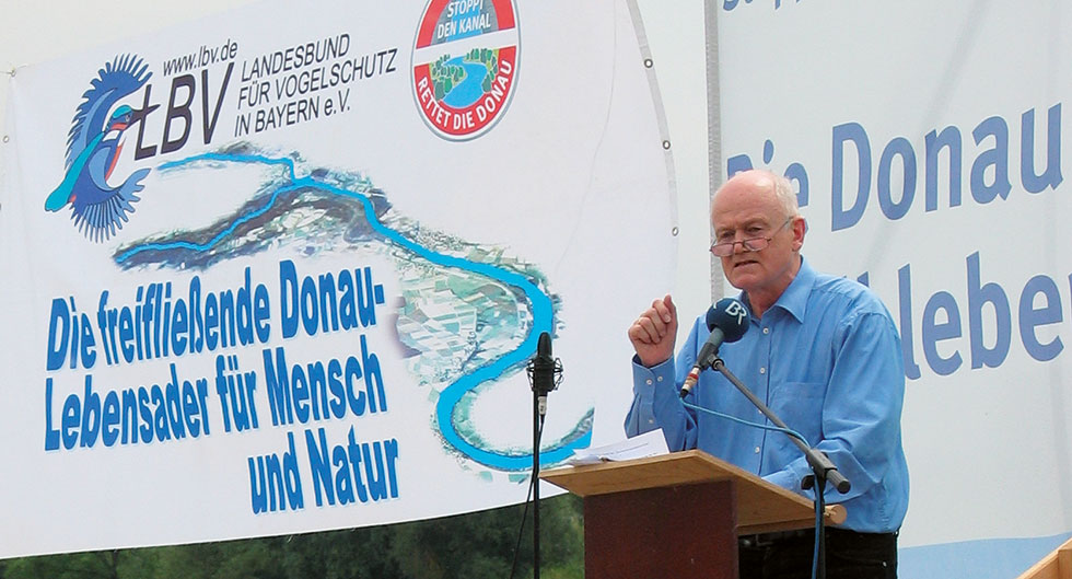 Alois Glück beim sitzt auf einem Stein bei einer Bergwanderung bei sonnigem Wetter.