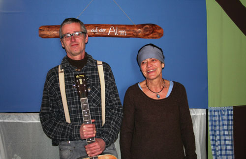 Die Künstler Bettina und Jochen Nistler von der werkstatt kesslfligga mit Gitarre. Im Hintergrund die Bühne.