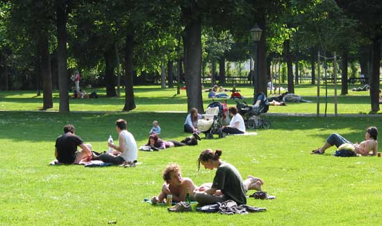 Stadtpark Burggarten: Viele Menschen liegen und sitzen auf Decken, haben Getränke und Essen dabei und unterhalten sich.