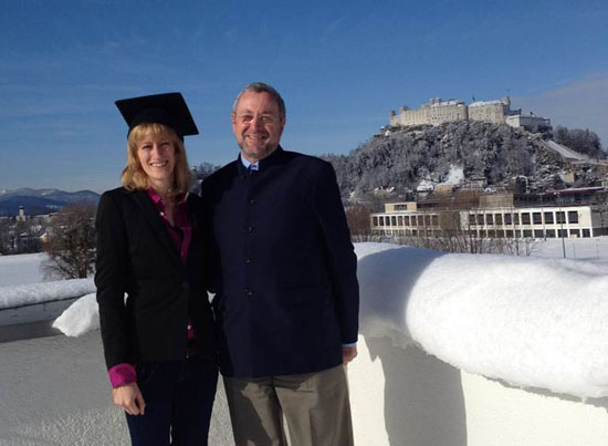 Bildinhalt: Frau Martina Artmann mit Doktorhut und Herr Professor Breuste vor der Kulisse der Festung Salzburg.