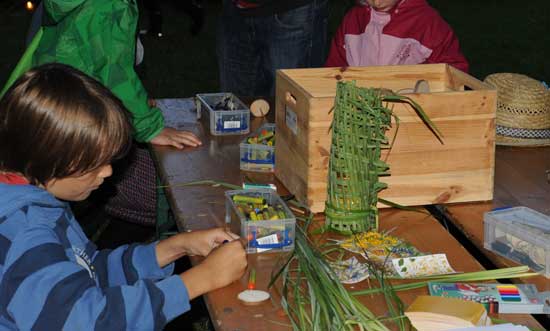 Mehrere Kinder sitzen an einem Tisch mit vielen Natur-Materialien und basteln.